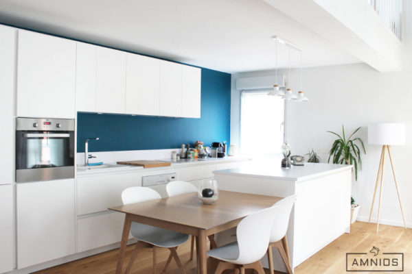 Cuisine blanche et bleue ouverte sur la salle à manger, rénovation AMNIOS à Grenoble